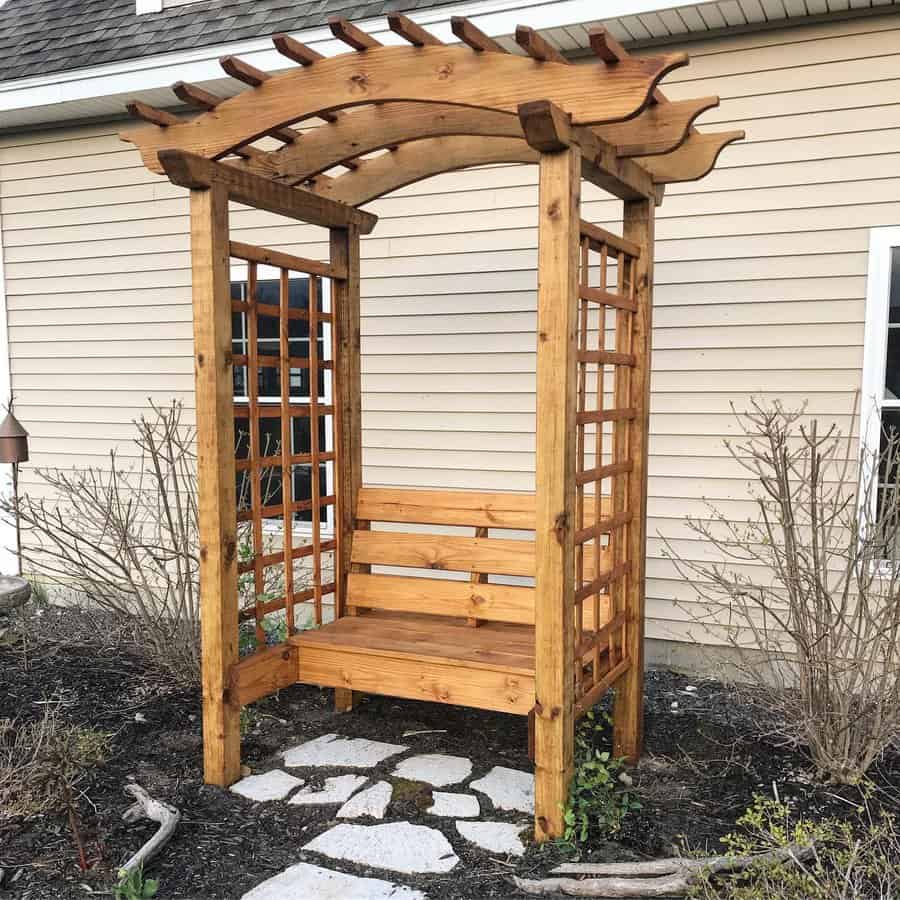 Wooden arbor with bench on stone path