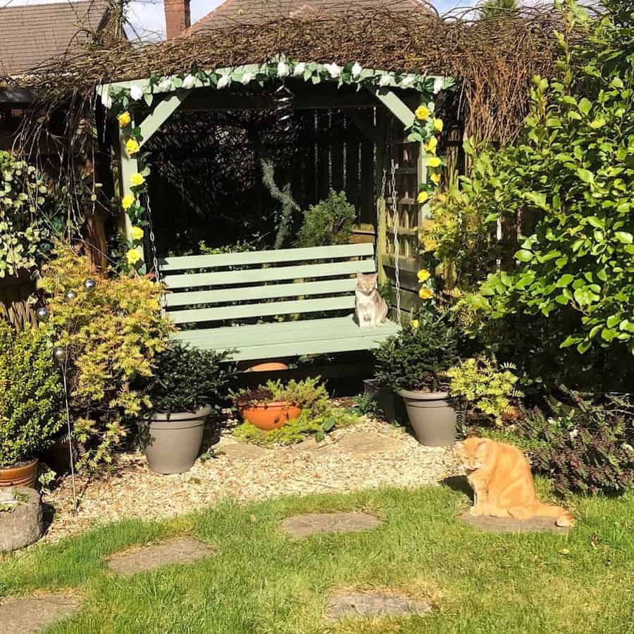 Arbor bench with cats in sunny garden