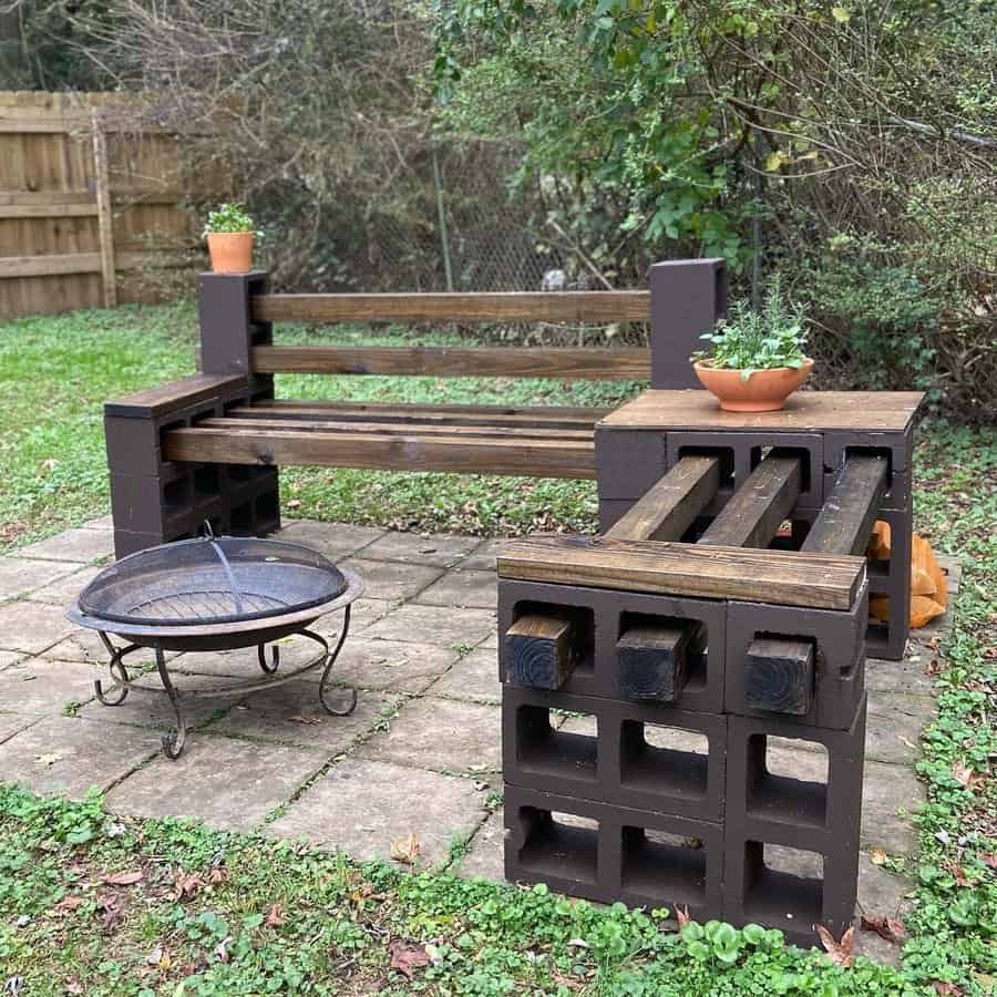 DIY outdoor seating area with cinder block and wood bench, matching table, and fire pit on a patio, creating a cozy backyard setup