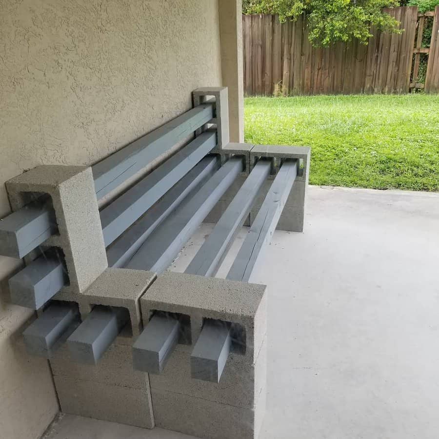 DIY cinder block and wooden beam bench painted in sleek gray, creating a modern and sturdy outdoor seating area under a covered patio