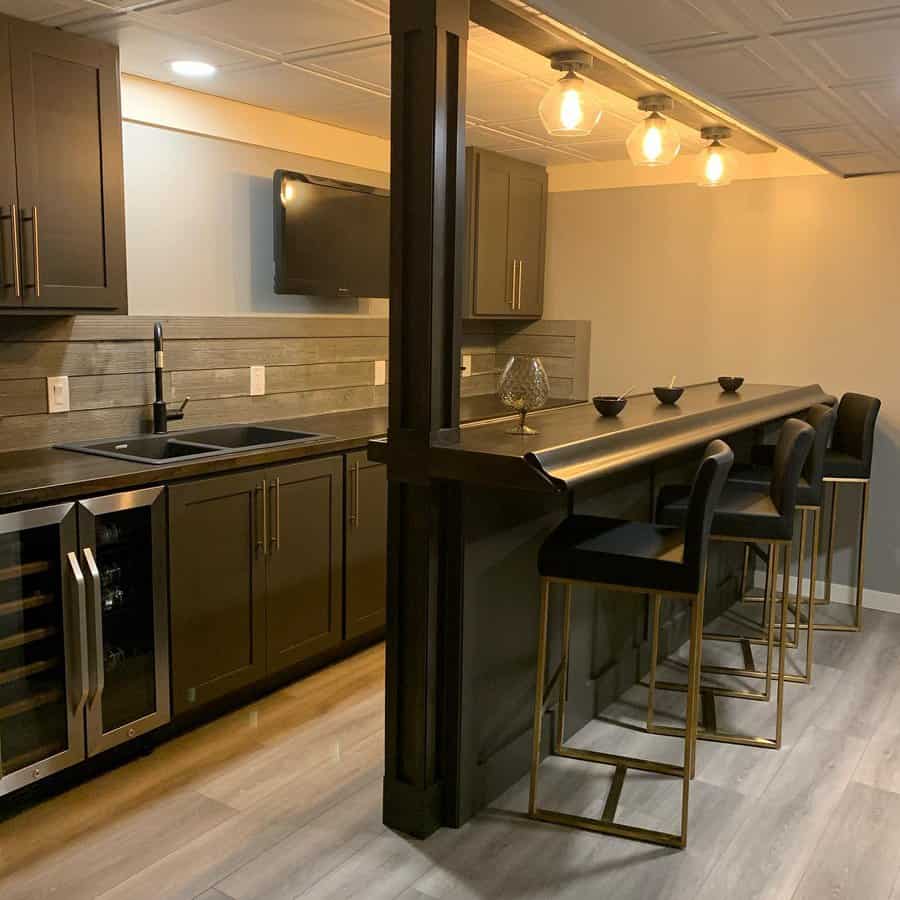 Modern basement bar with dark cabinetry and seating