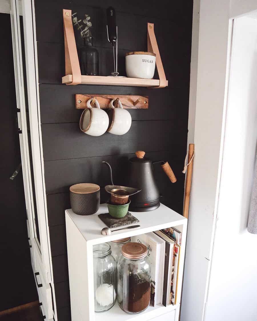 A sleek RV kitchen corner with minimalist shelves, neatly arranged coffee mugs, a kettle, and storage jars, creating an organized and functional space.