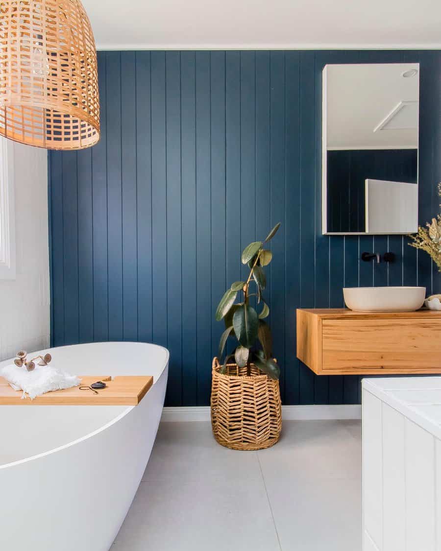 Modern bathroom with blue walls, wooden vanity, and freestanding tub