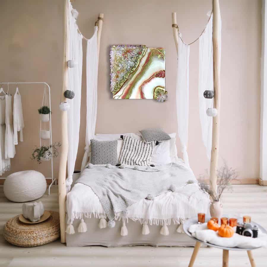 Bohemian-style canopy bed with sheer white drapes, natural wood posts, tassel bedding, and cozy neutral decor for a serene bedroom retreat