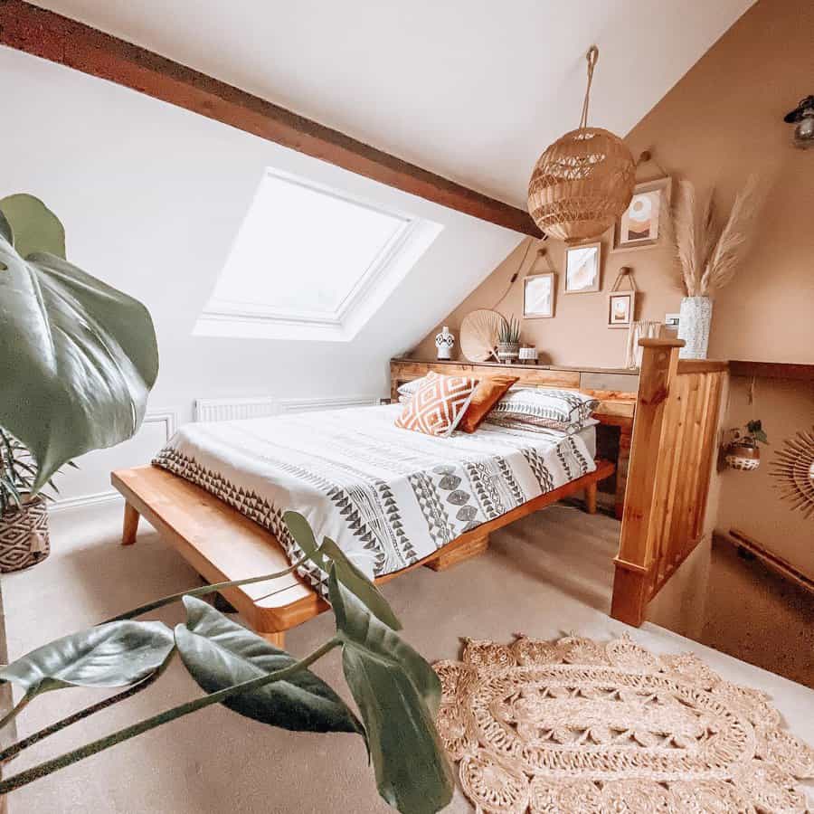 Boho attic bedroom with warm earth tones, woven accents, and a skylight. Wooden furniture and greenery add a cozy, natural touch.