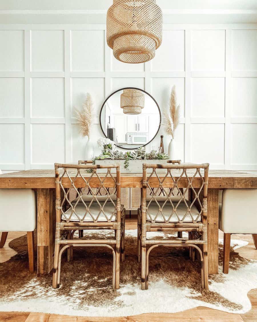 Cozy dining room with wooden table, wicker chairs, round mirror, and a woven pendant light. Neutral tones and plants accent the decor