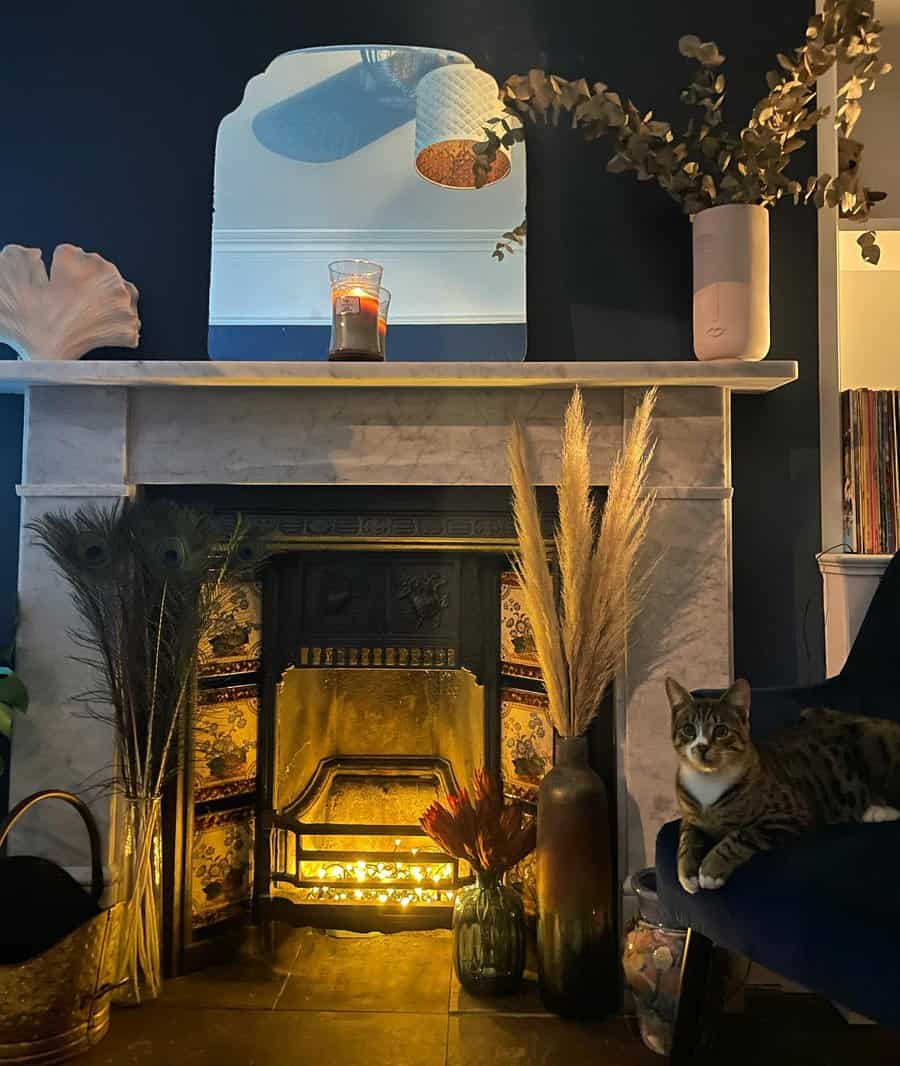 Cozy living room with a lit fireplace, candle on the mantel, decorative plants, and a cat sitting on a chair next to it