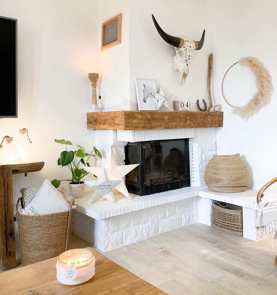 Cozy living room with fireplace, boho decor, and a cow skull on the wall; warm lighting, plants, woven baskets, and candles adorn the space