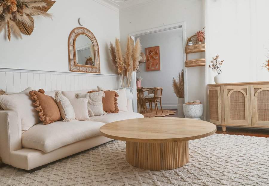 Bohemian living room with beige tones, a round wooden coffee table, and boho decor