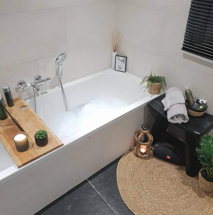 Large white bathtub with soft rug and potted plants