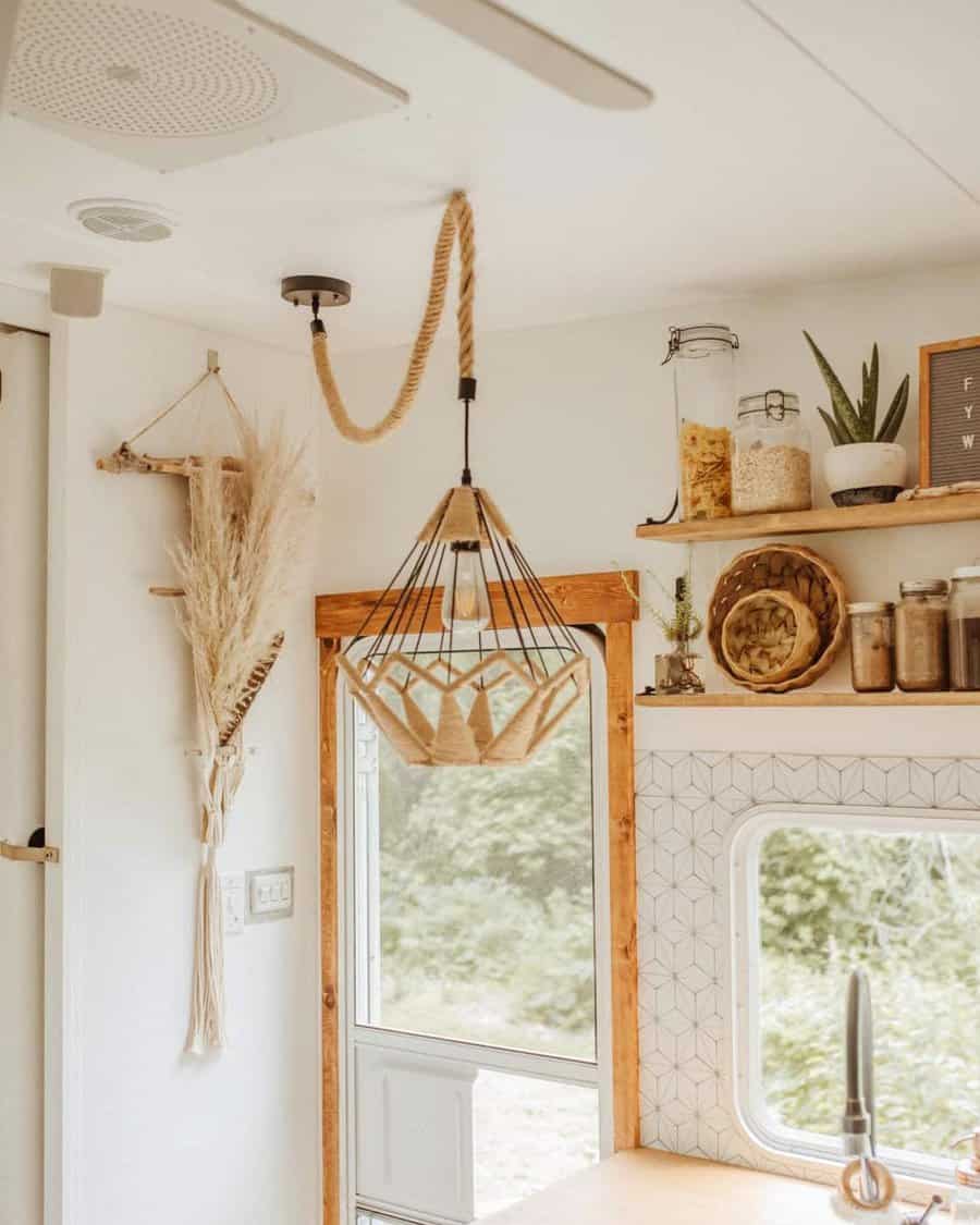 A boho-inspired RV kitchen with a unique rope pendant light, natural decor elements, geometric tiles, and wooden shelves filled with plants and jars.