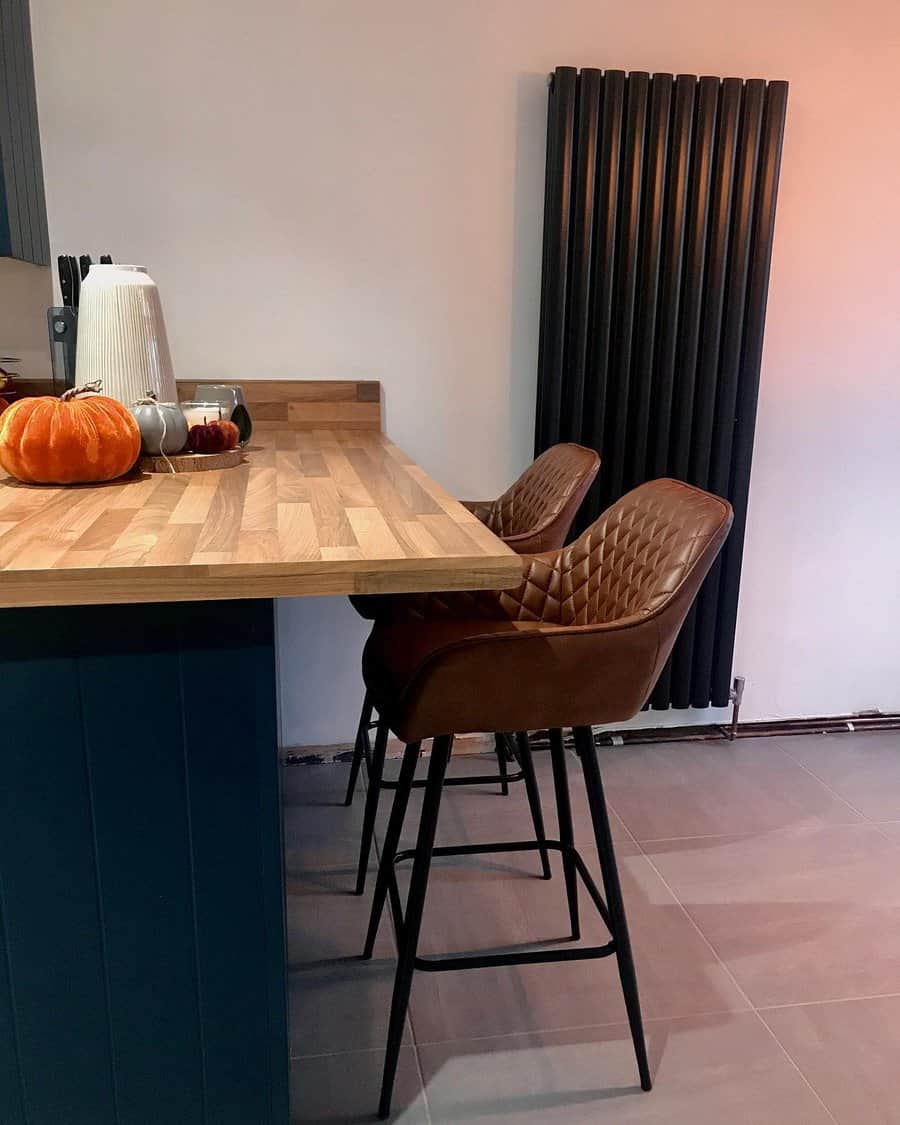 Cozy kitchen with a wooden breakfast bar, brown quilted barstools, and autumn decor, creating a warm and inviting atmosphere