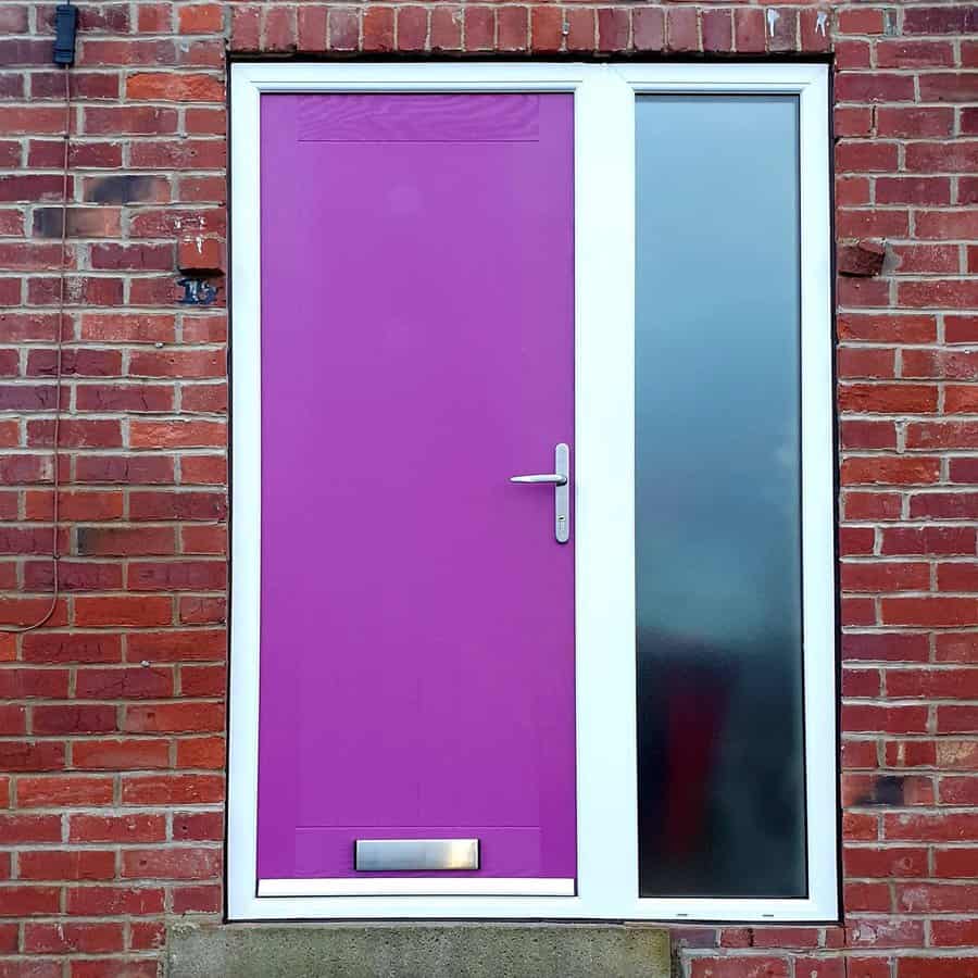 A brick wall with a purple door and adjacent frosted glass panel