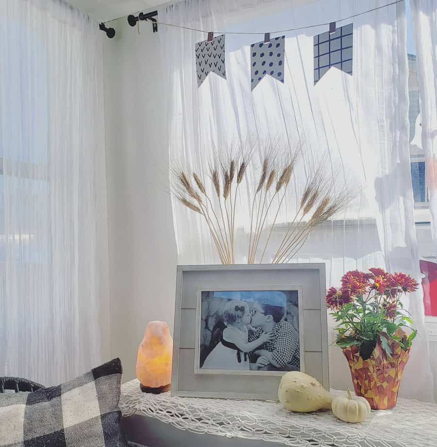 A bright and airy RV corner with a framed photo, wheat decor, colorful potted plants, a salt lamp, and playful banner accents.