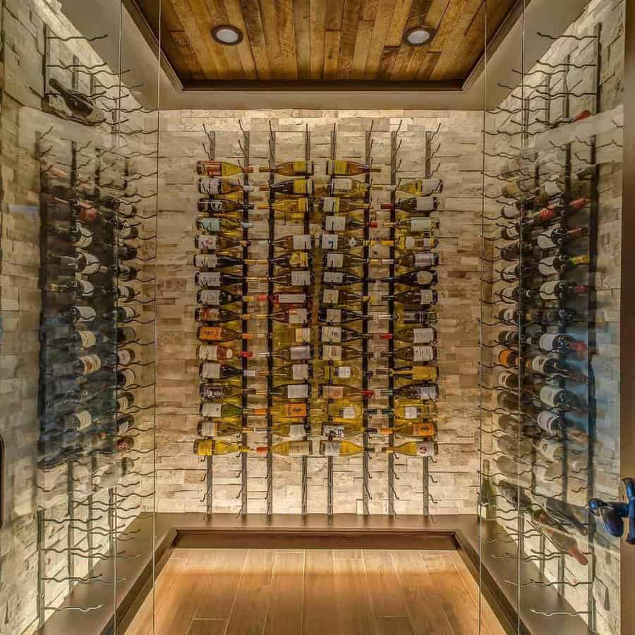 A wine cellar with bottles arranged on vertical racks, surrounded by brick walls and wooden floors and ceiling