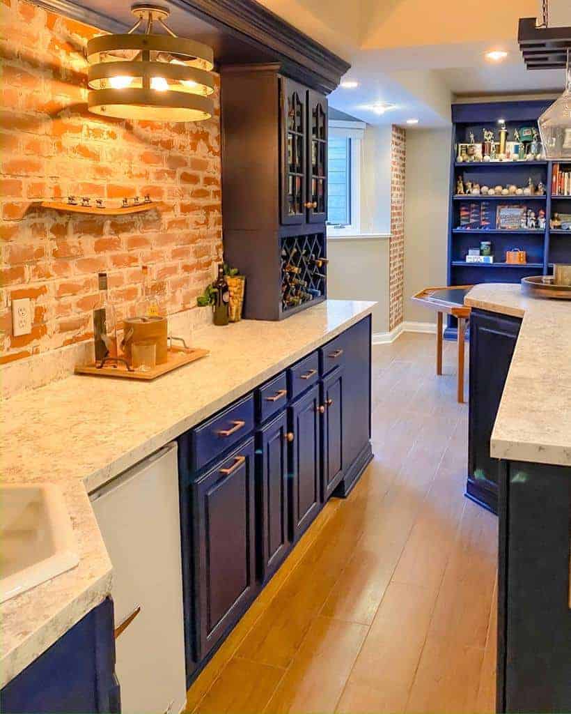 Rustic home bar with navy cabinets, exposed brick wall, built-in wine rack, and warm lighting for a cozy and stylish ambiance