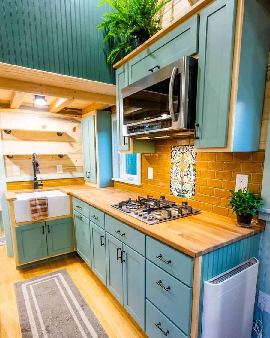 Tiny house kitchen with teal cabinets and wood accents