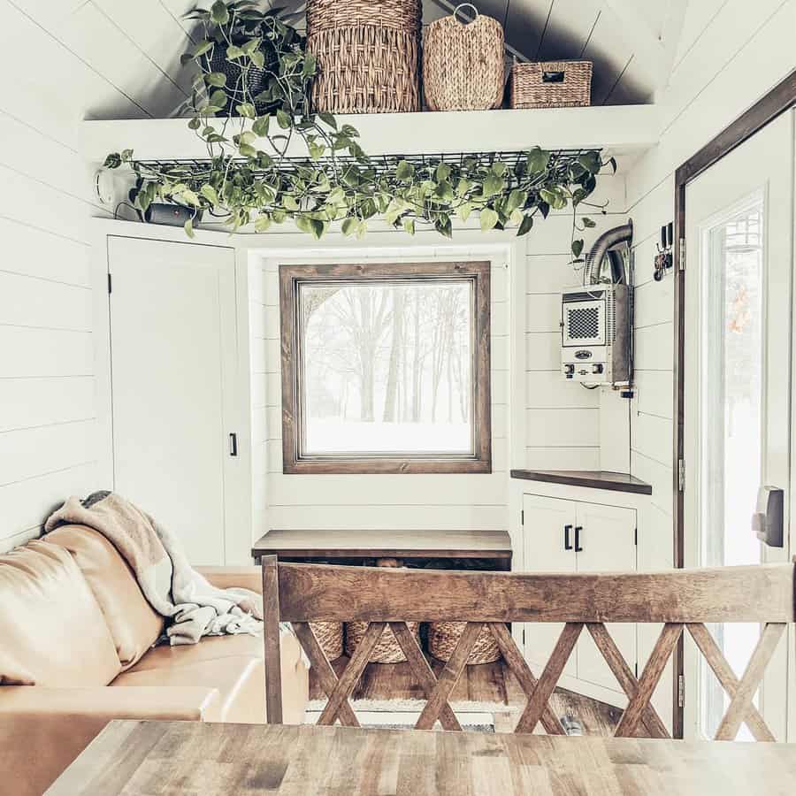 White tiny house interior with plants and wooden table