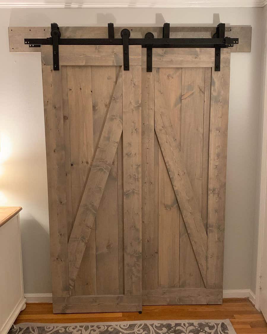 Rustic wooden barn-style bypass doors with black hardware bring farmhouse charm to this cozy space, adding warmth and character to the room