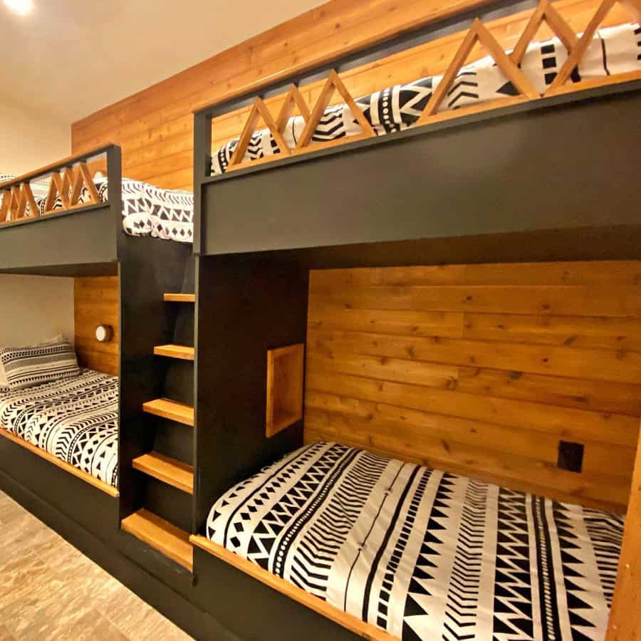 Cozy bunk beds with patterned black and white bedding, wooden accents, and a built-in ladder against a wood-paneled wall