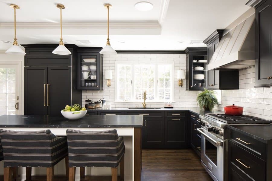 Modern kitchen with black cabinets, white island, and backsplash, and stainless appliances