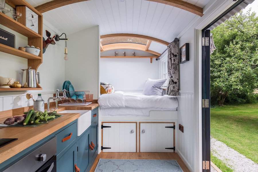 Tiny home interior with kitchen and elevated bed by open door