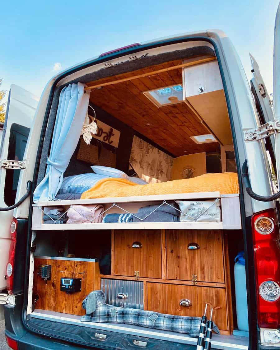 Van conversion with cozy sleeping nook and wooden storage