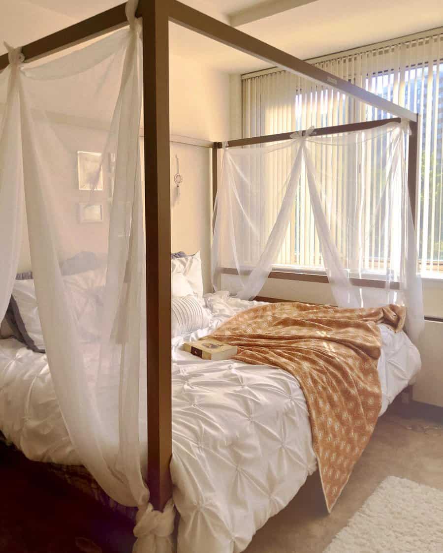 Cozy canopy bed with sheer white drapes, tufted bedding, and warm accents, creating a dreamy and relaxing bedroom retreat with natural light