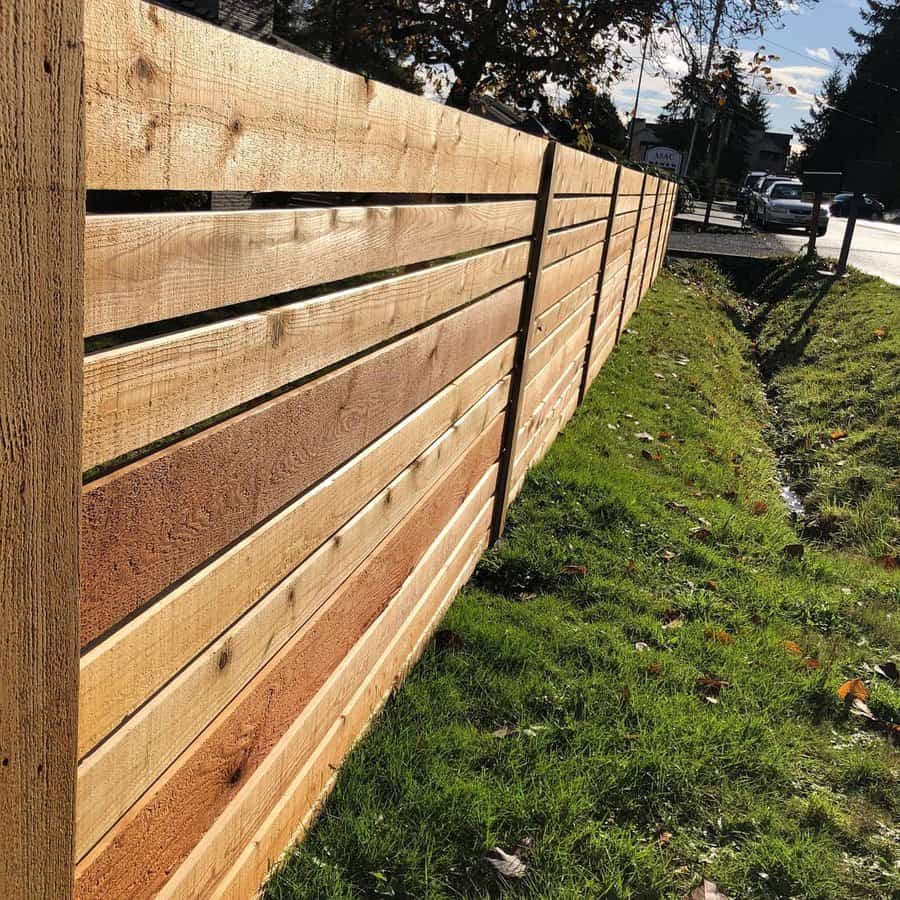 New cedar horizontal fence along a grassy roadside