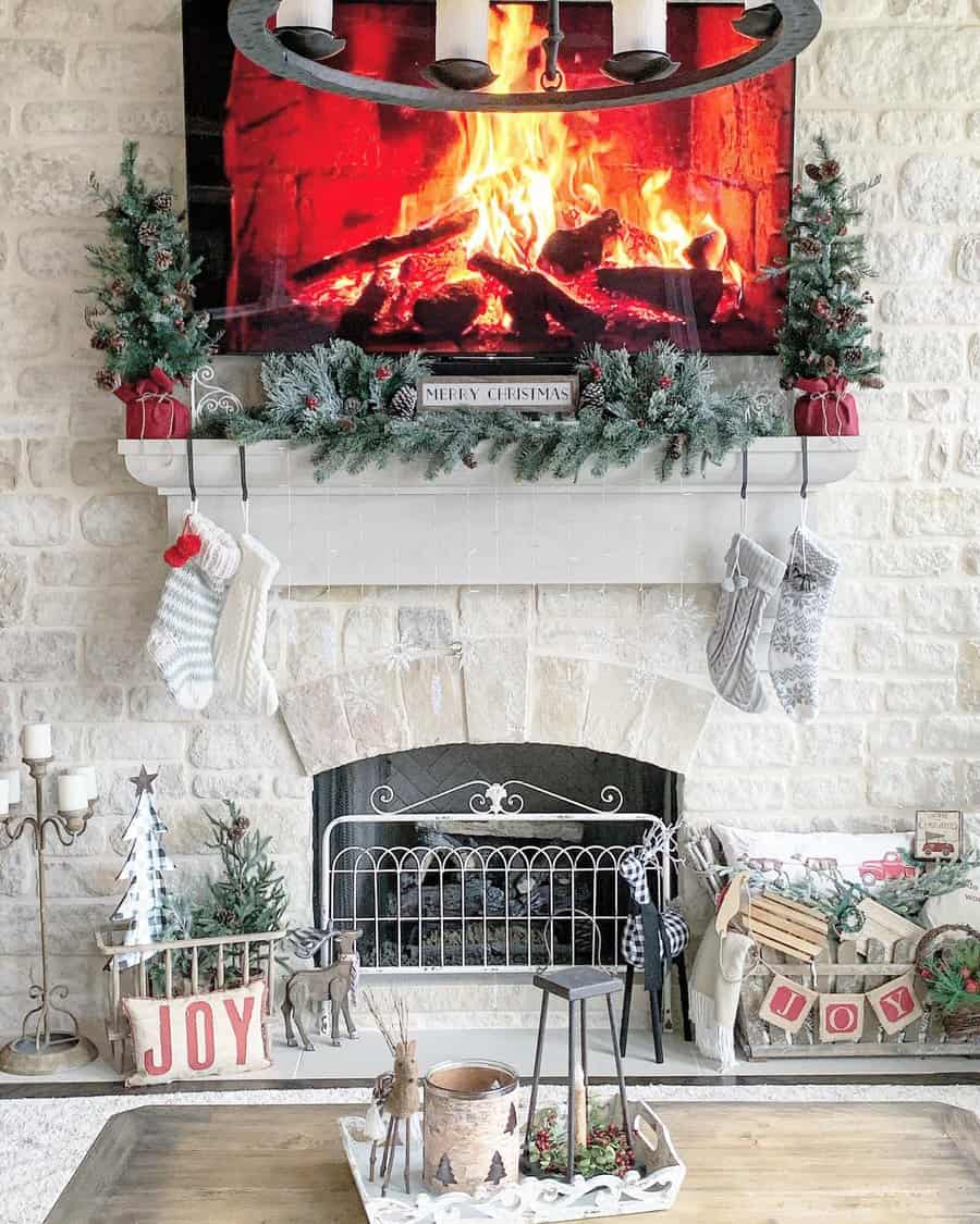 Cozy living room with a fireplace, stockings hanging on the mantel, a "Merry Christmas" sign, and holiday decorations around