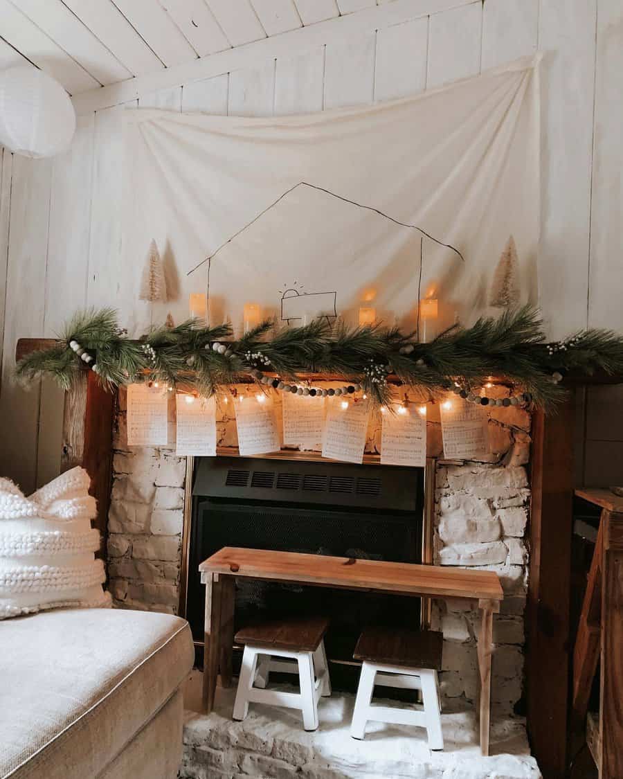 Cozy fireplace with garland, lights, candles, and sheet music; white walls, a bench, and small stools add a rustic touch