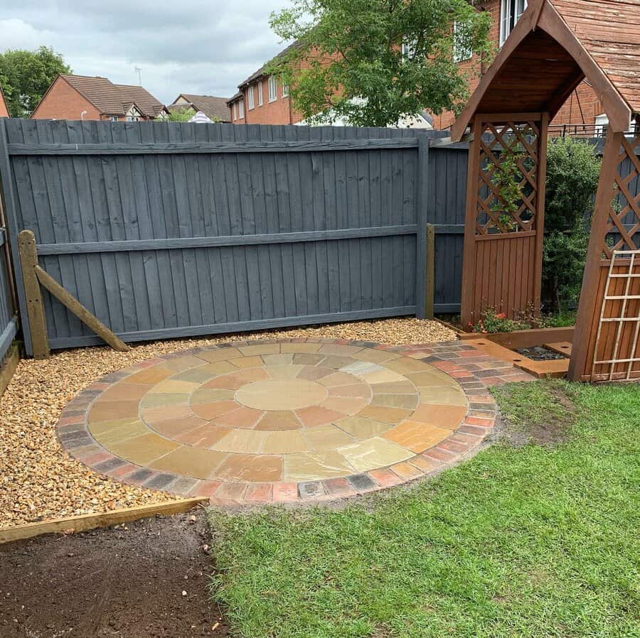 Colorful circular brick patio in a gravel and grass garden