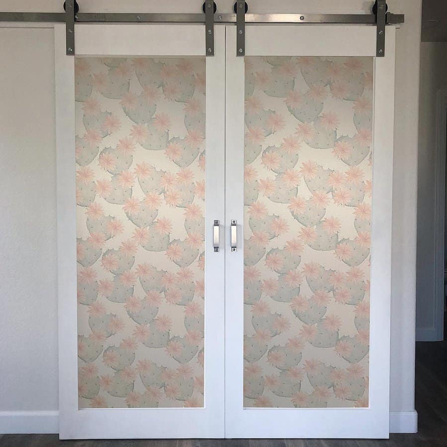 White barn-style sliding closet doors with soft floral-patterned panels add a charming and elegant touch to this modern space