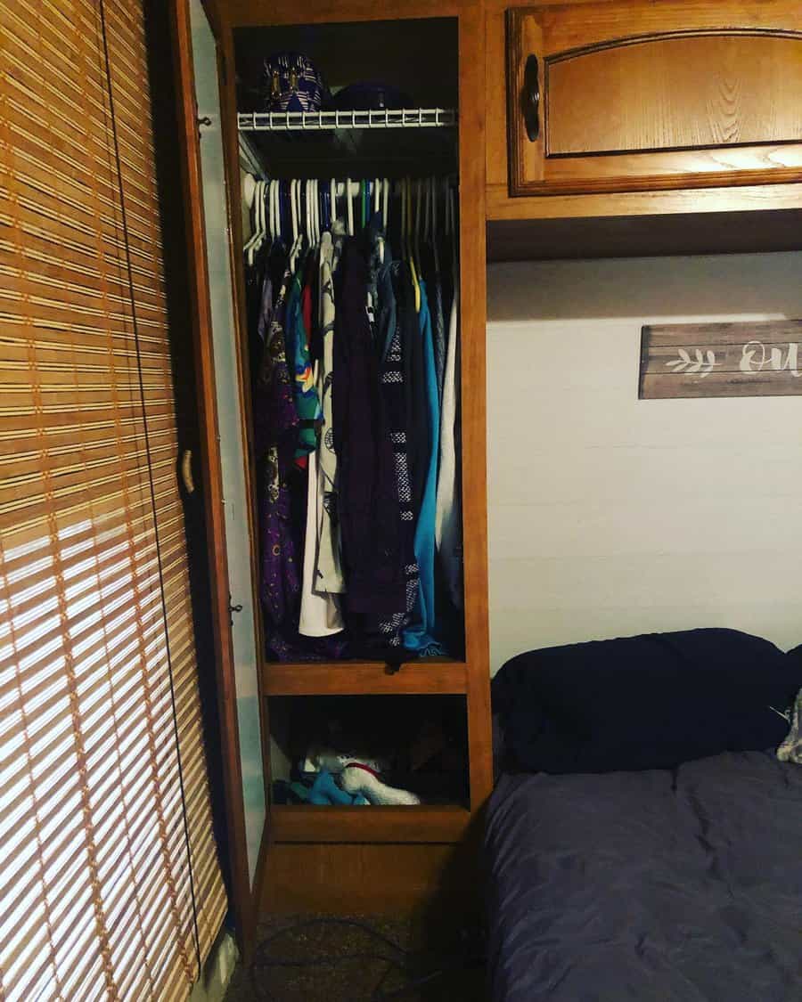 Compact wooden RV closet with clothes and bamboo blind