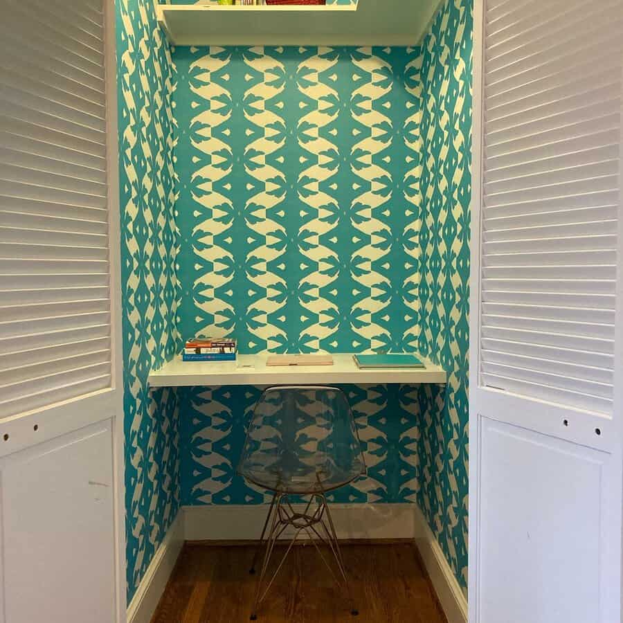 Closet office with vibrant blue patterned wallpaper