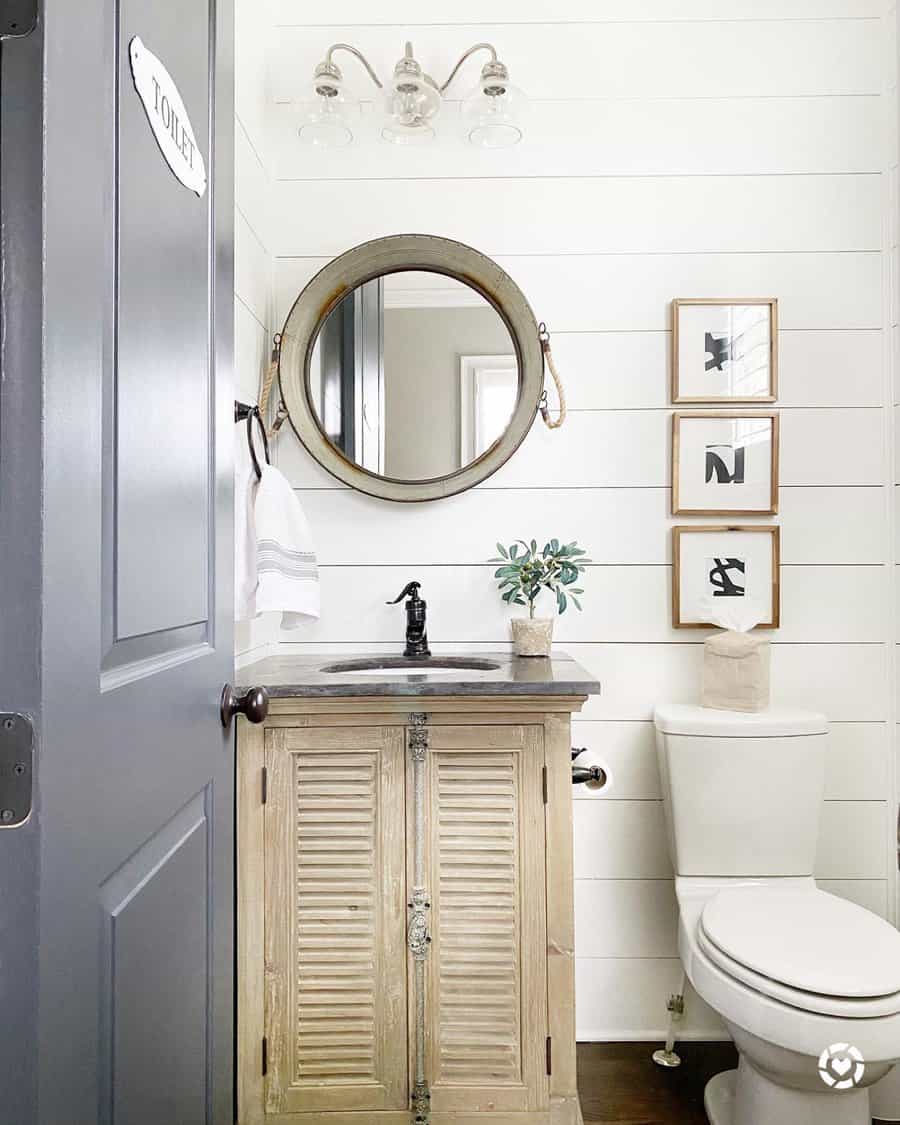 Charming coastal farmhouse bathroom with rustic vanity and round mirror