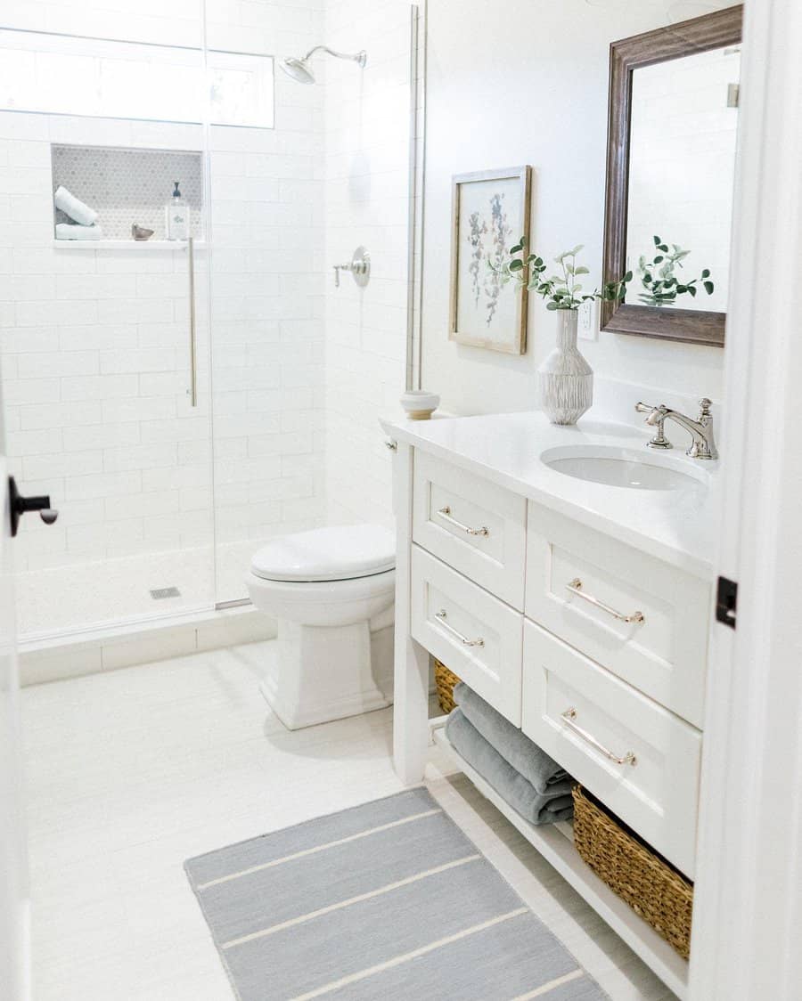 Bright white bathroom with glass shower and wooden framed mirror