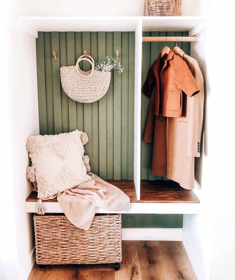 Cozy entryway bench with a sage green paneled wall, woven storage basket, and wooden coat rack, styled with neutral textiles and rattan decor