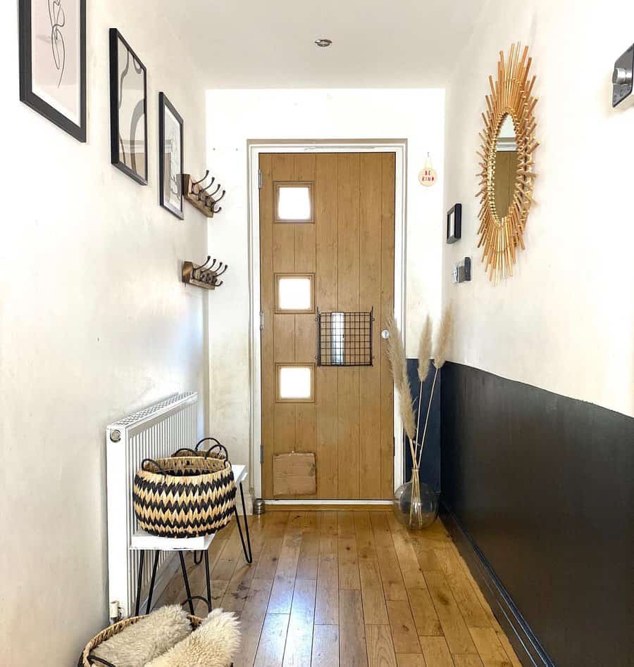 Modern rustic entryway with a wooden door, black-and-white decor, woven baskets, pampas grass, and a sunburst mirror for a cozy touch