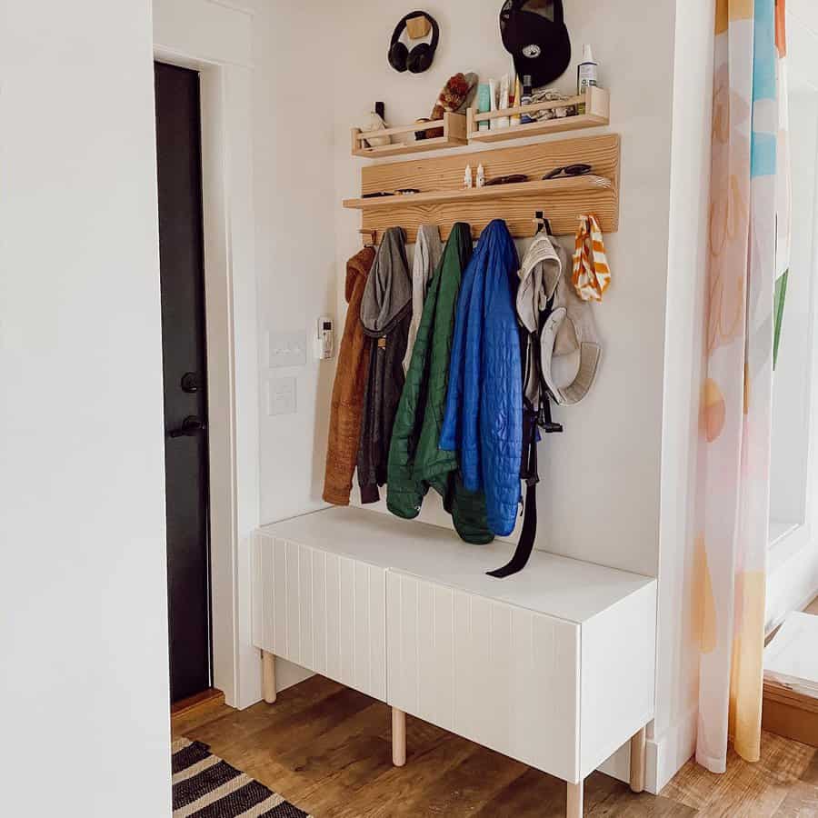 Minimalist entryway with a white storage bench, wooden wall-mounted coat rack, and open shelves for essentials, blending function and style