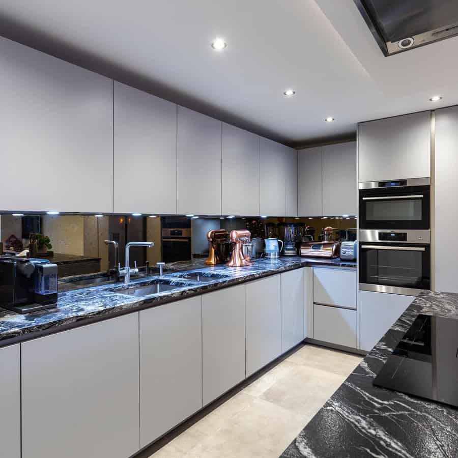 Modern kitchen with gray cabinets, black marble countertops, and stainless appliances