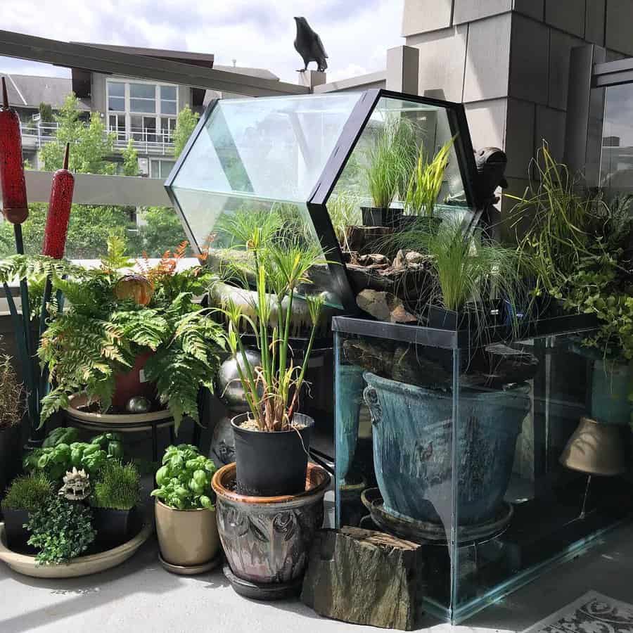 Modern balcony garden with glass terrariums, lush greenery, potted plants, and a small water feature, creating a serene urban oasis