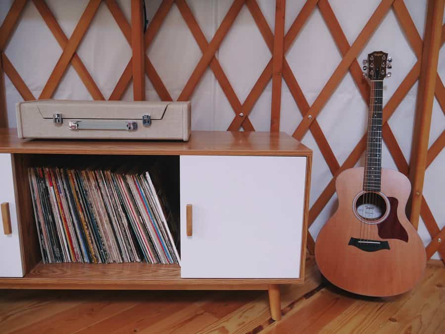 Cabinet with vinyls and guitar against yurt wall