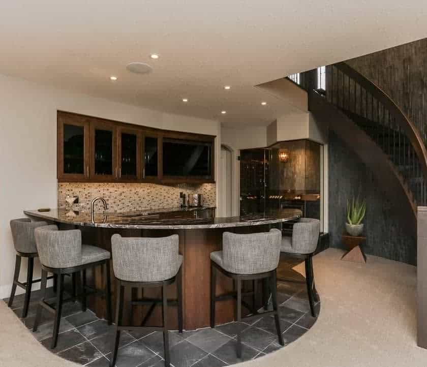 Curved bar with stools under a sweeping staircase