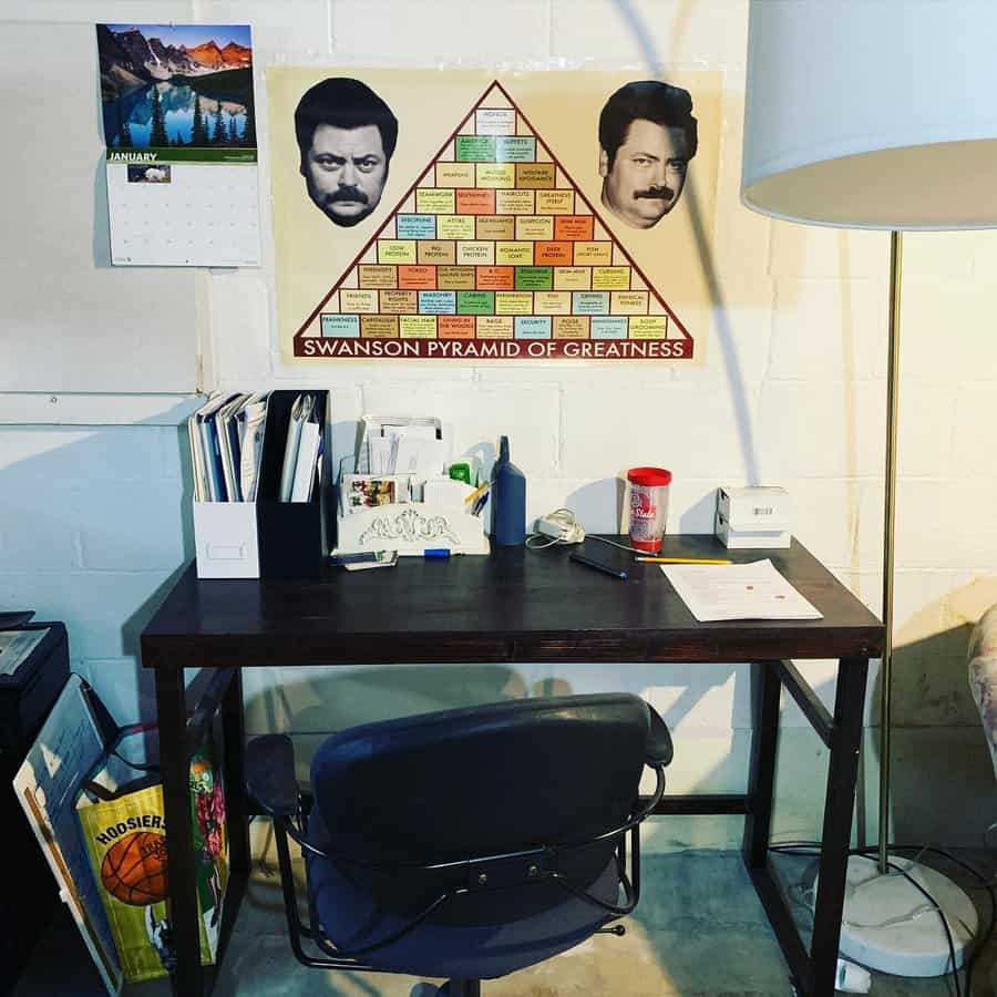 Industrial-style basement office with a dark wood desk, black chair, and motivational wall art, creating a simple yet functional workspace