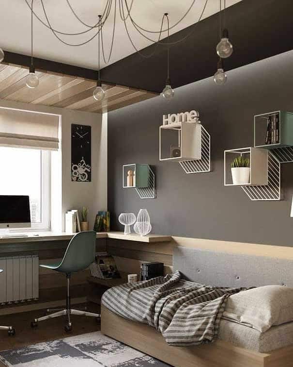 Modern bedroom with a desk, chair, and computer by a window, featuring wire wall shelves, hanging bulbs, and a cozy bed