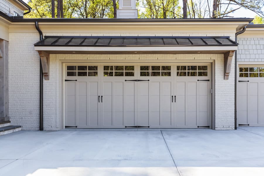 Triple beige garage doors on white brick home