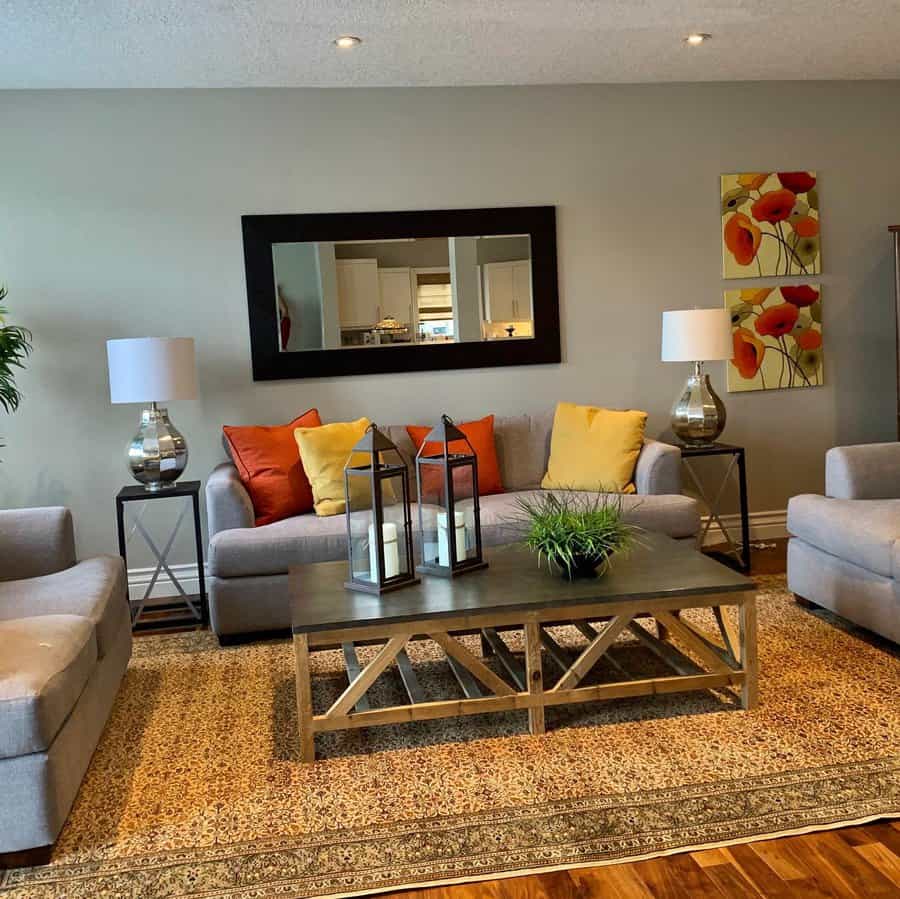 Modern living room with grey sofa, armchairs, and accents of yellow and red decor.