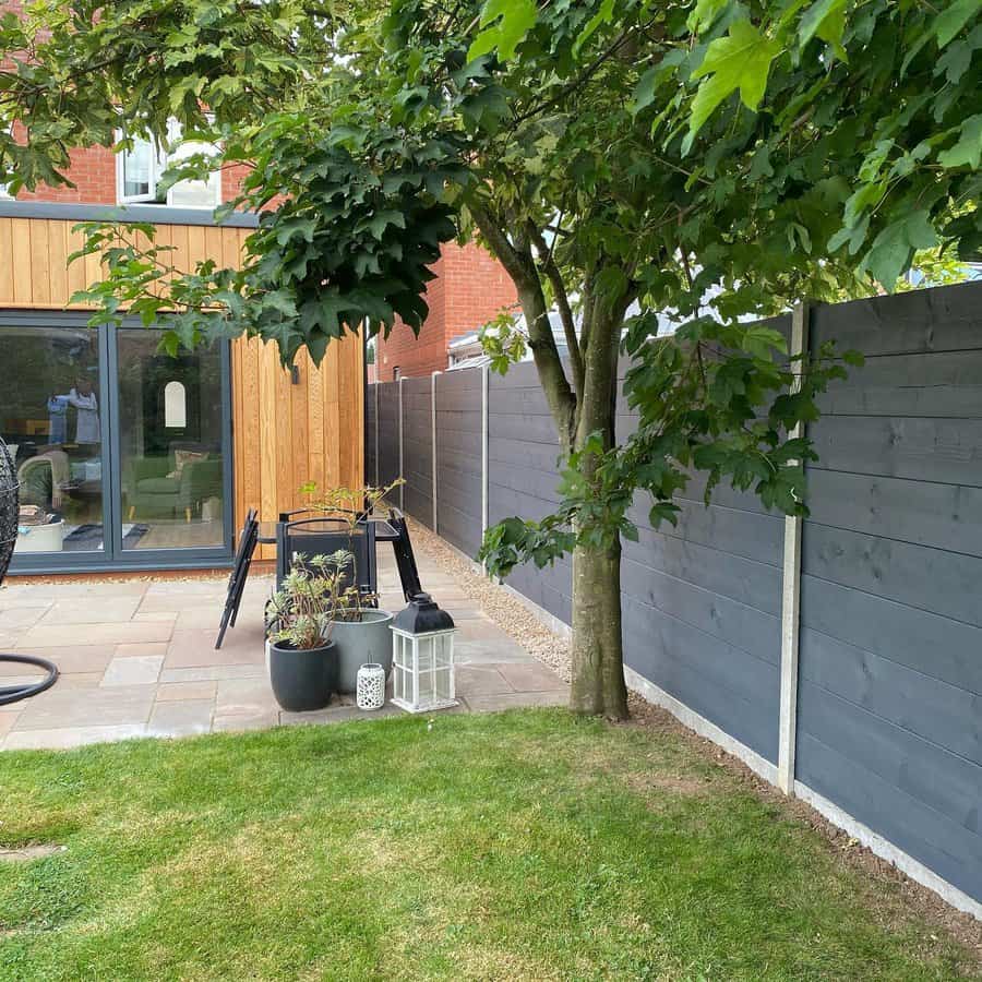 Modern grey fence in a backyard with green lawn and tree