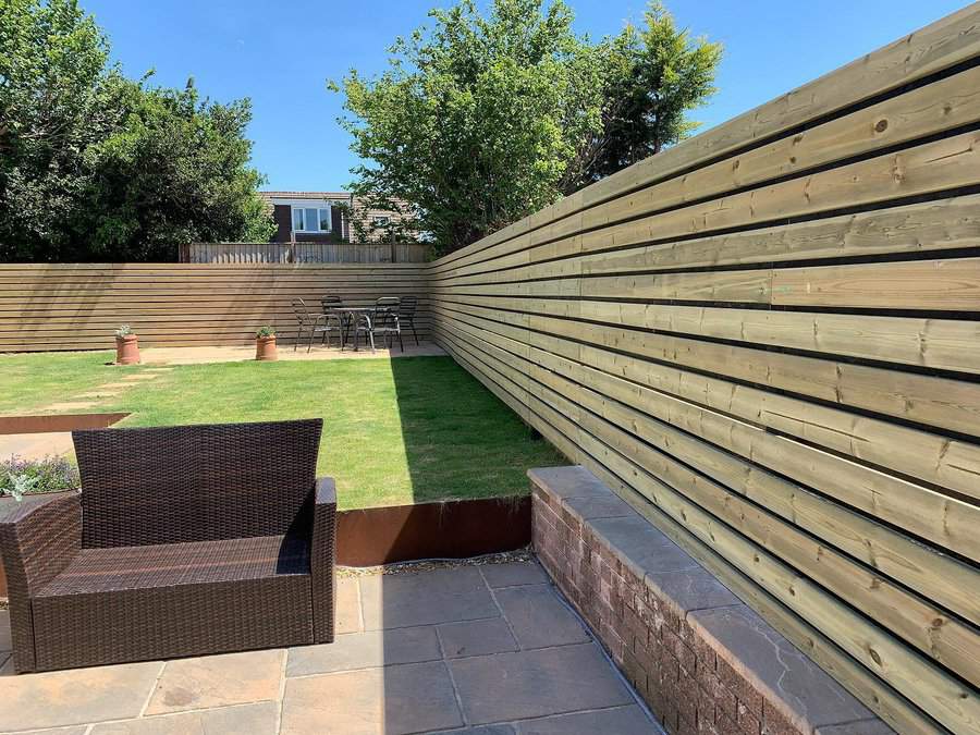 Angled view of a garden with horizontal wooden fence and patio